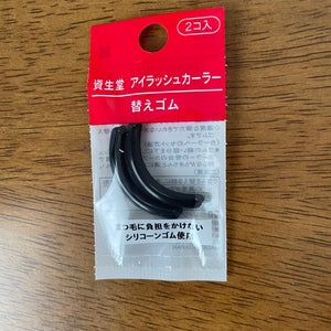 Empaque de repuestos para rizador de pestañas SHISEIDO sobre una superficie de madera.