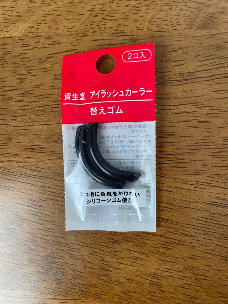 Empaque de repuestos para rizador de pestañas SHISEIDO sobre una superficie de madera.